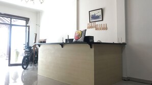 A reception desk with a framed picture, a chandelier, and a motorcycle outside. - OYO 90183 Mess Kavaleri Heritage (Jakarta)