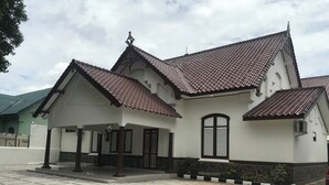 A building with a tiled roof, a covered entrance, and a stone wall. - OYO 90183 Mess Kavaleri Heritage (Jakarta)