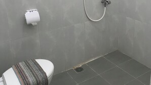 A small, modern bathroom with a shower, toilet, and hand dryer. - OYO 90183 Mess Kavaleri Heritage (Jakarta)