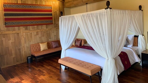 A room with a bed, a bench, a sofa, and a wall hanging. - Bali Sunshine Inn Nusa Dua (Nusa Dua)