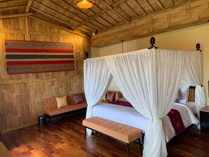 A room with a bed, a bench, a sofa, and a wall hanging. - Bali Sunshine Inn Nusa Dua (Nusa Dua)