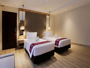 A hotel room with two beds, a wardrobe, a desk, and a mirror.