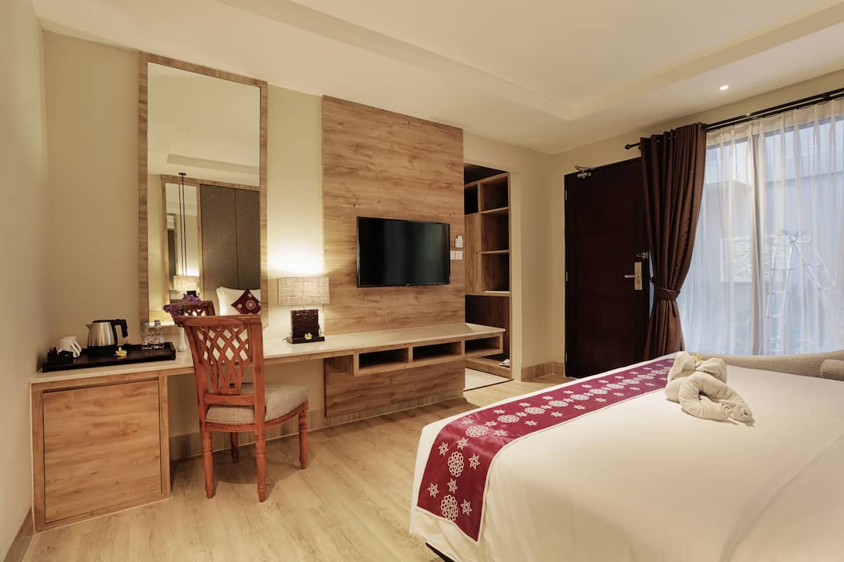Una habitació d'hotel amb llit, escriptori amb cadira, televisió i armari.