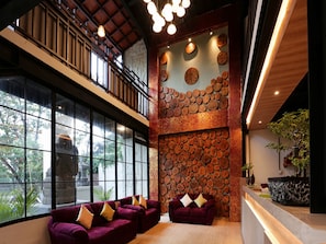 A spacious interior with a high ceiling, large windows, and a seating area with purple sofas.