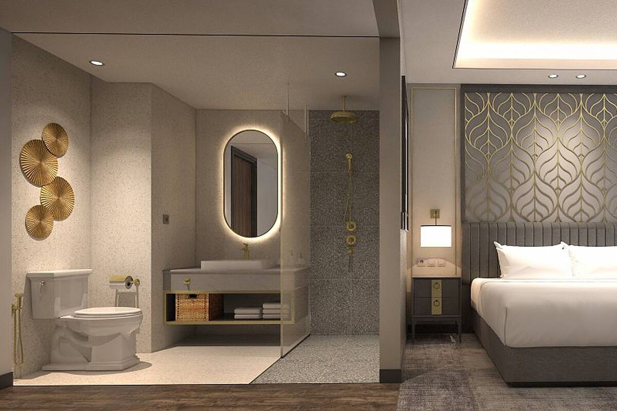 Une chambre d’hôtel moderne dotée d’un grand lit, d’une salle de bain séparée, d’une coiffeuse et d’un coin salon près de la fenêtre.