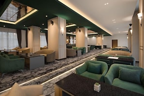 Eine Hotelhalle mit einer zentralen Sitzgruppe, einem Empfangsbereich und einer Bar.