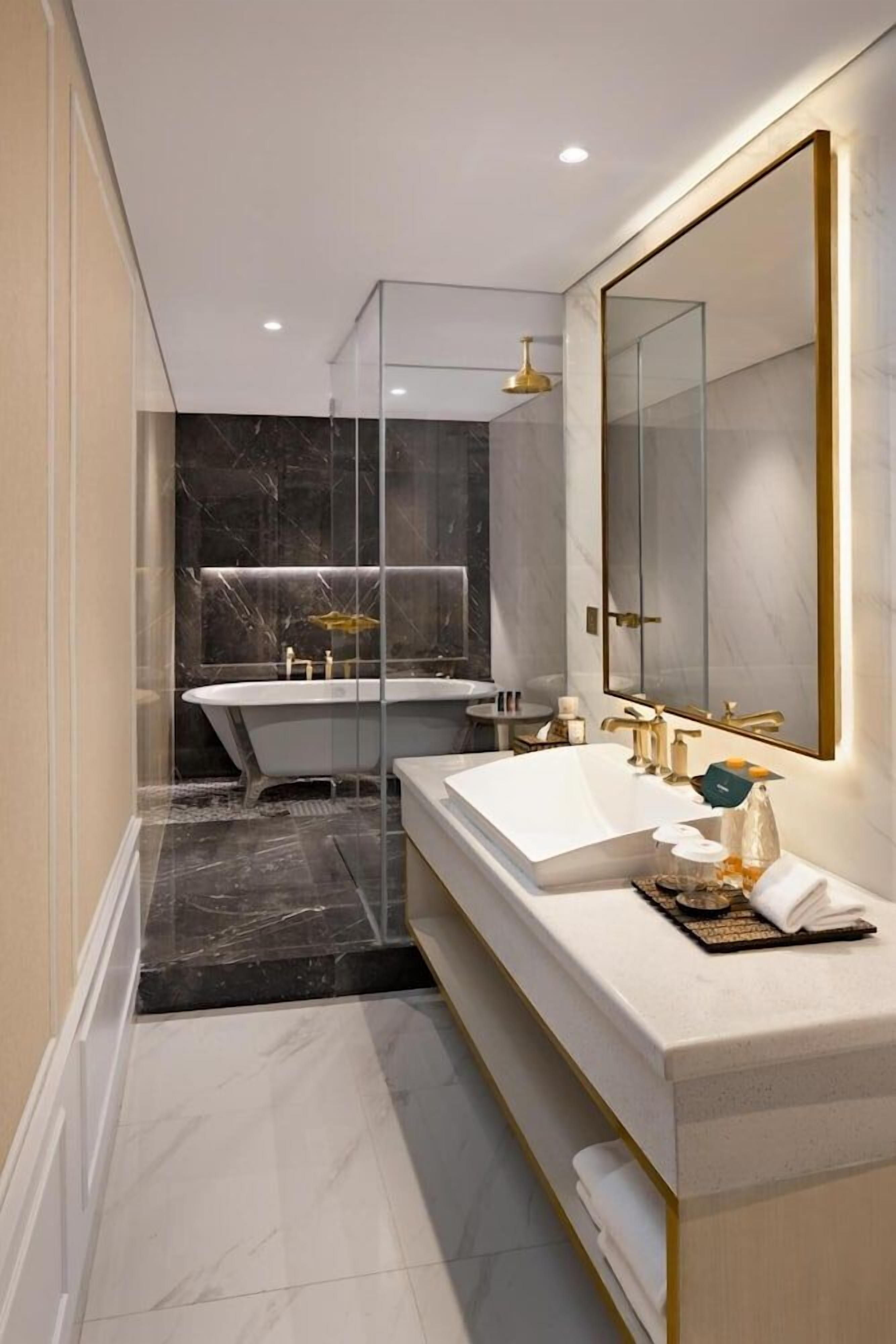 A modern bathroom with a freestanding bathtub, a double sink vanity, and a large mirror.