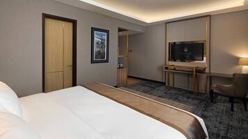 A hotel room with a bed, a desk, a television, and a chair.
