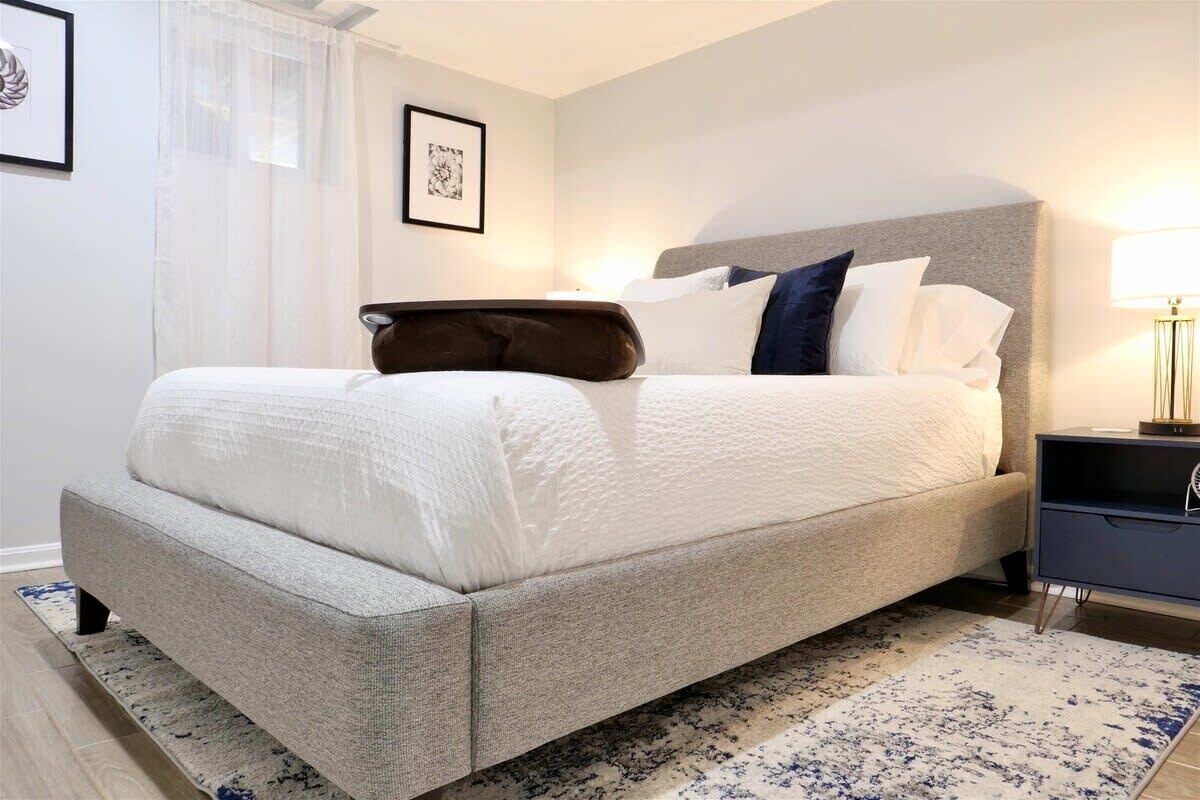 Een keurig opgemaakt slaapkamer met een bed, nachtkastjes en een vloerkleed.