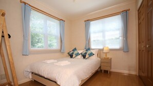 Un dormitorio con cama, mesita de noche, lámpara y cortinas.