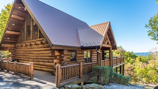 A log cabin with a metal roof, wooden deck, and a scenic view. - Magnolia Bearadise #311 (Sevierville)