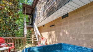 A hot tub with a wooden deck, a set of stairs leading to a covered area, and a brick wall. - Magnolia Bearadise #311 (Sevierville)