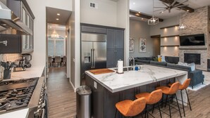 A modern kitchen with a central island, stainless steel appliances, and a dining area in the background. - Luxury Retreat w/Views: Putting Green/Game Room/Infinity Pool & More! (Escondido)