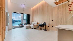 Una sala de estar moderna con un ventanal grande, un sofá, una mesita de centro y un escritorio con una silla.