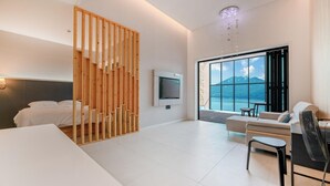Una habitación de hotel moderna con cama, televisión, piano y un amplio ventanal con vistas a la montaña.