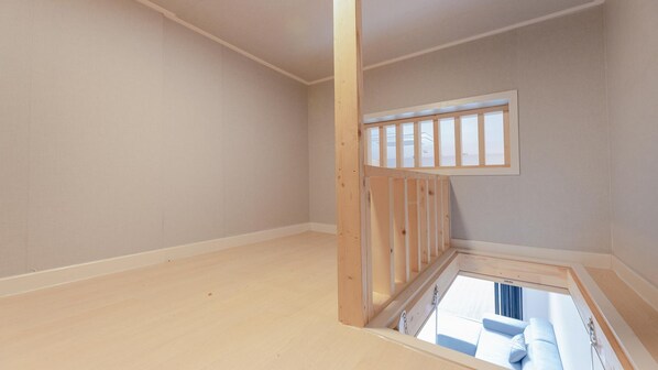 A room with a sloped ceiling, a window, and a wooden floor.