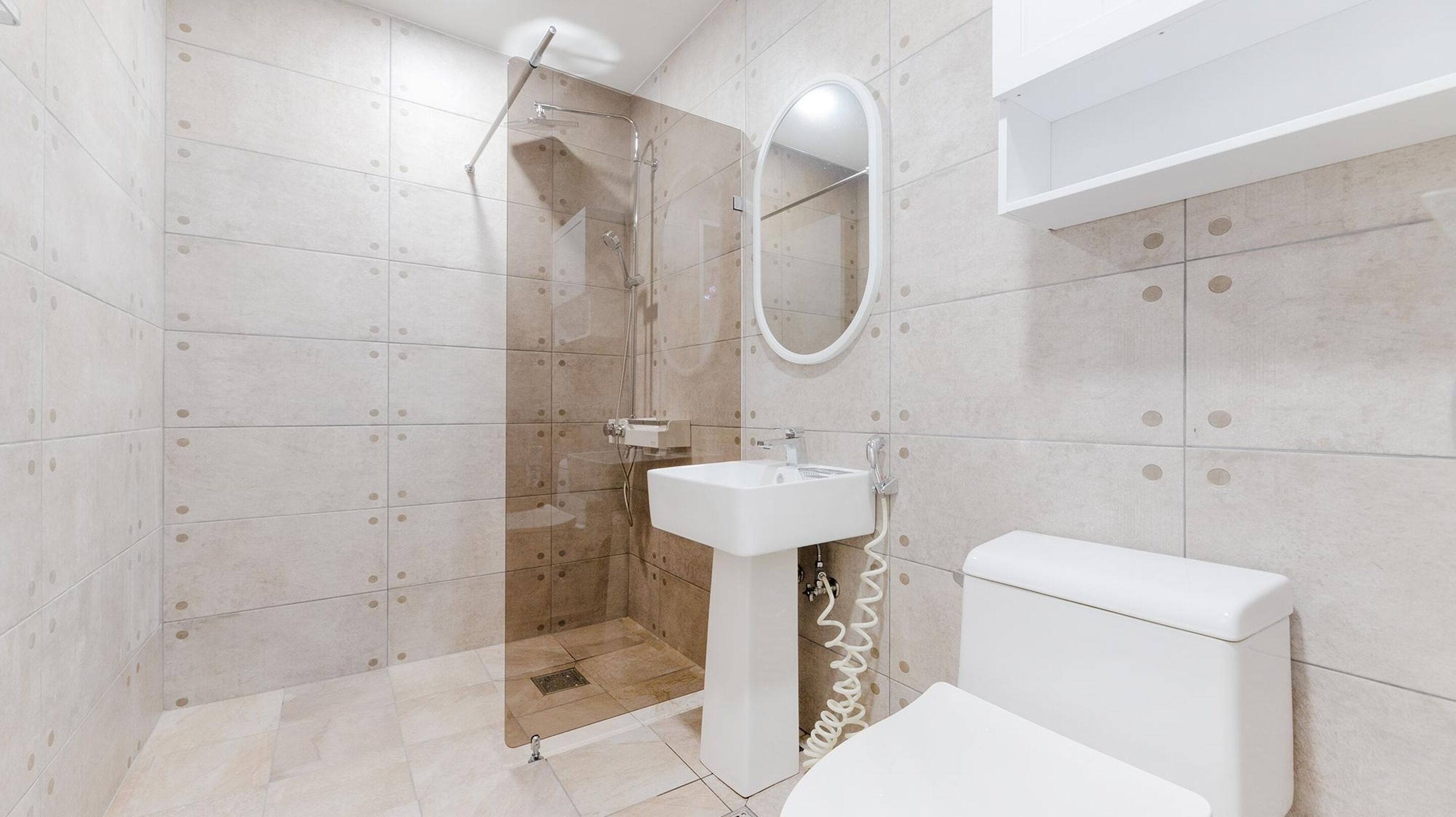 A modern bathroom with a glass-enclosed shower, a white sink, and a toilet.