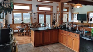 Een ruime keuken met houten kastjes, een groot eiland en een vloer van natuursteen.