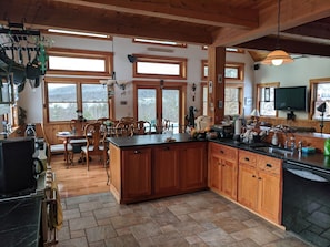 Un'ampia cucina con mobili in legno, un'isola grande e un pavimento in pietra.