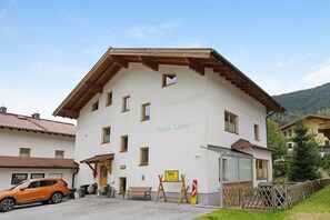 Un bâtiment à deux étages, avec une enseigne indiquant « Haus Lowe », un banc en bois et une voiture garée devant.