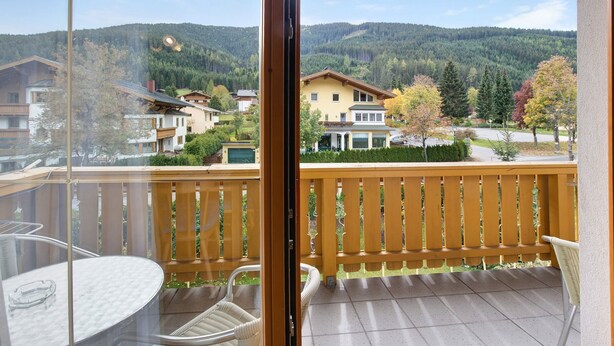 Un balcon donnant sur un quartier résidentiel, avec une table et des chaises.