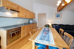 Ett kök med träskåp, en inbyggd ugn och ett matbord med en blå duk.