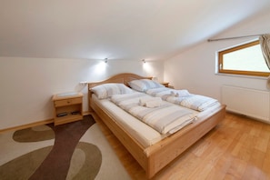 Une chambre à coucher avec un lit en bois, une table de chevet, un radiateur et une fenêtre.