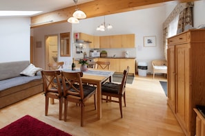 Un salon chaleureux avec une table à manger en bois, des chaises et un canapé gris.