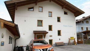 A building with multiple windows, a sign reading 'Haus Lowe,' and a parked car.