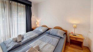 A double bed with striped bedding, two bedside tables with lamps, and a window with sheer curtains. - "Haus Lowe Appartement 1 Stock Nr 2" with Mountain View (Filzmoos)