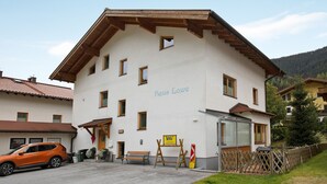 A two-story building with a sign reading 'Haus Lowe,' a wooden bench outside, and a parked car. - "Haus Lowe Appartement 1 Stock Nr 2" with Mountain View (Filzmoos)
