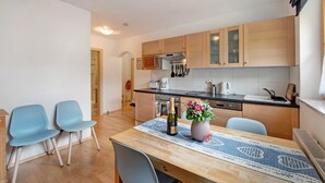 A compact kitchen with wooden cabinets, a microwave, and a dining area with two chairs and a table. - "Haus Lowe Appartement 1 Stock Nr 3" with Mountain View (Filzmoos)