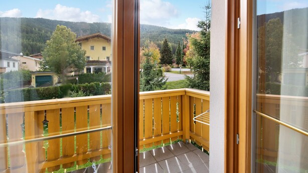 A balcony with a wooden railing, a view of a residential area, and a mountain in the background. - "Haus Lowe Appartement 1 Stock Nr 3" with Mountain View (Filzmoos)