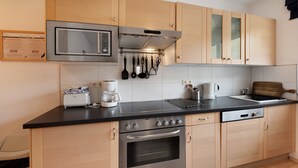 A modern kitchen with stainless steel appliances, wooden cabinets, and a black countertop. - "Haus Lowe Appartement 1 Stock Nr 3" with Mountain View (Filzmoos)