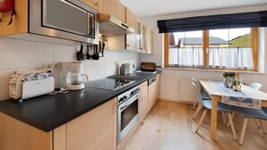 A modern kitchen with a built-in oven, a coffee maker, and a dining area with a table and chairs. - "Haus Lowe Appartement 1 Stock Nr 3" with Mountain View (Filzmoos)