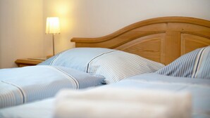 Una cama bien tendida con ropa de cama a rayas, cabecera de madera y lámpara de noche.