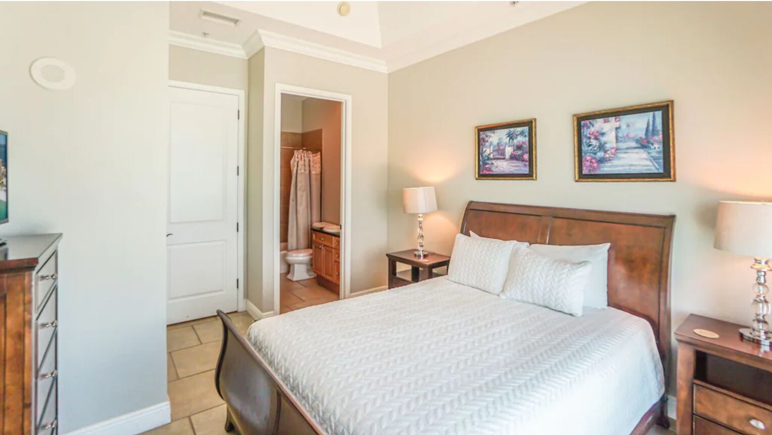 A hotel room with a bed, bedside tables, a wardrobe, and a bathroom visible through an open door.