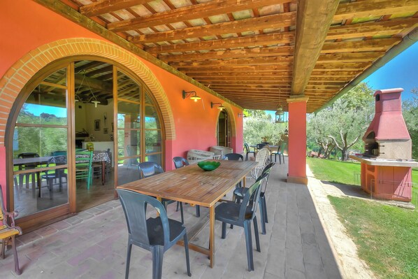 An outdoor patio with a wooden table and chairs, a brick archway, and a grill area. - Fienile, Montopoli Val D'Arno, Italy (Montopoli Val D'Arno)