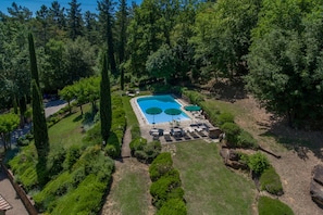 An aerial view of a landscaped area with a swimming pool, sun loungers, and a small deck area.