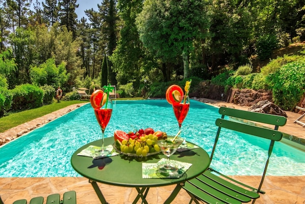 A poolside setting with a table, chairs, and a bench.