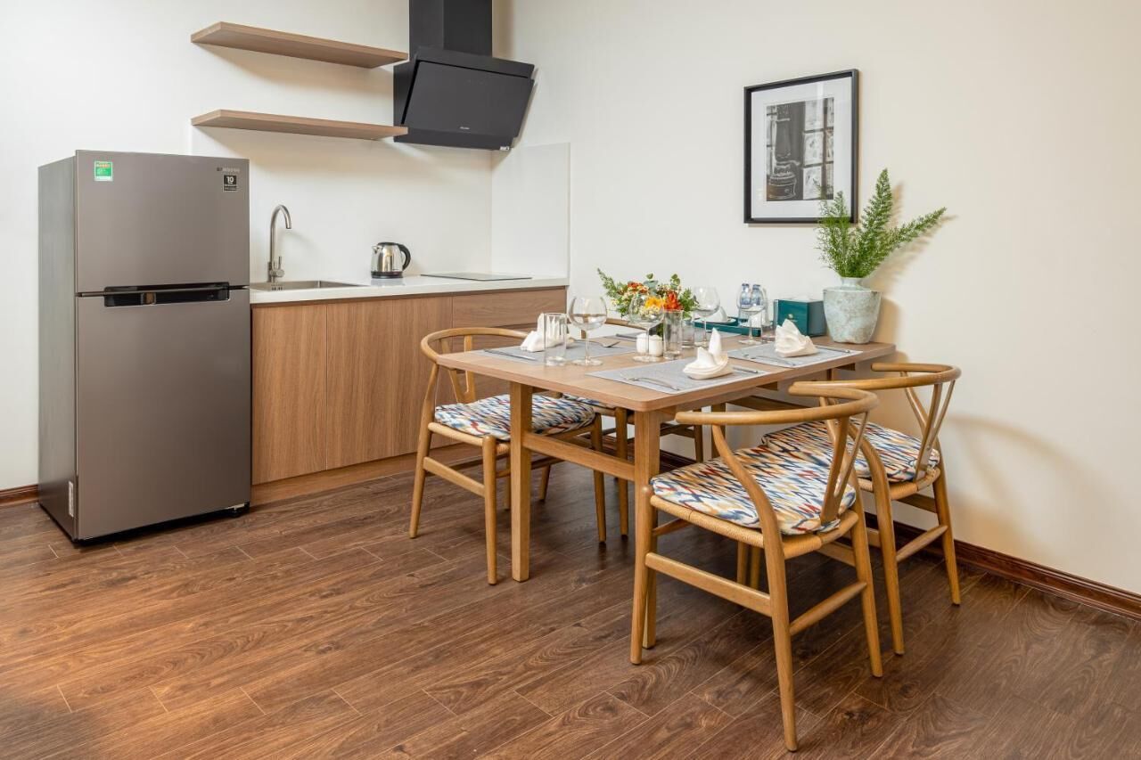 A compact kitchen with a built-in refrigerator, wooden cabinets, and a dining area with a table and chairs.