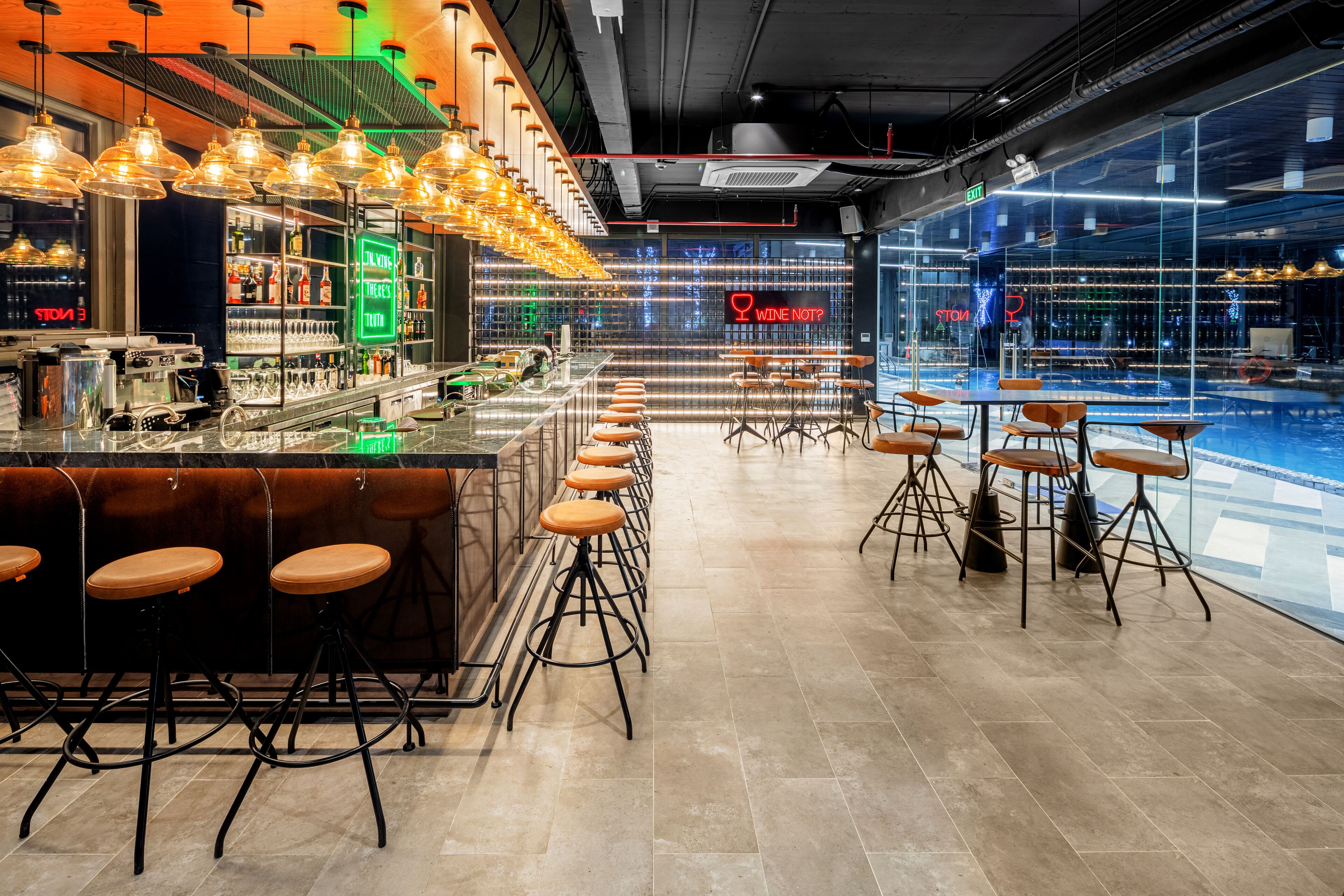 A bar area with stools, a counter, and a neon sign.