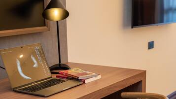 A wooden desk with a laptop, books, and a lamp.