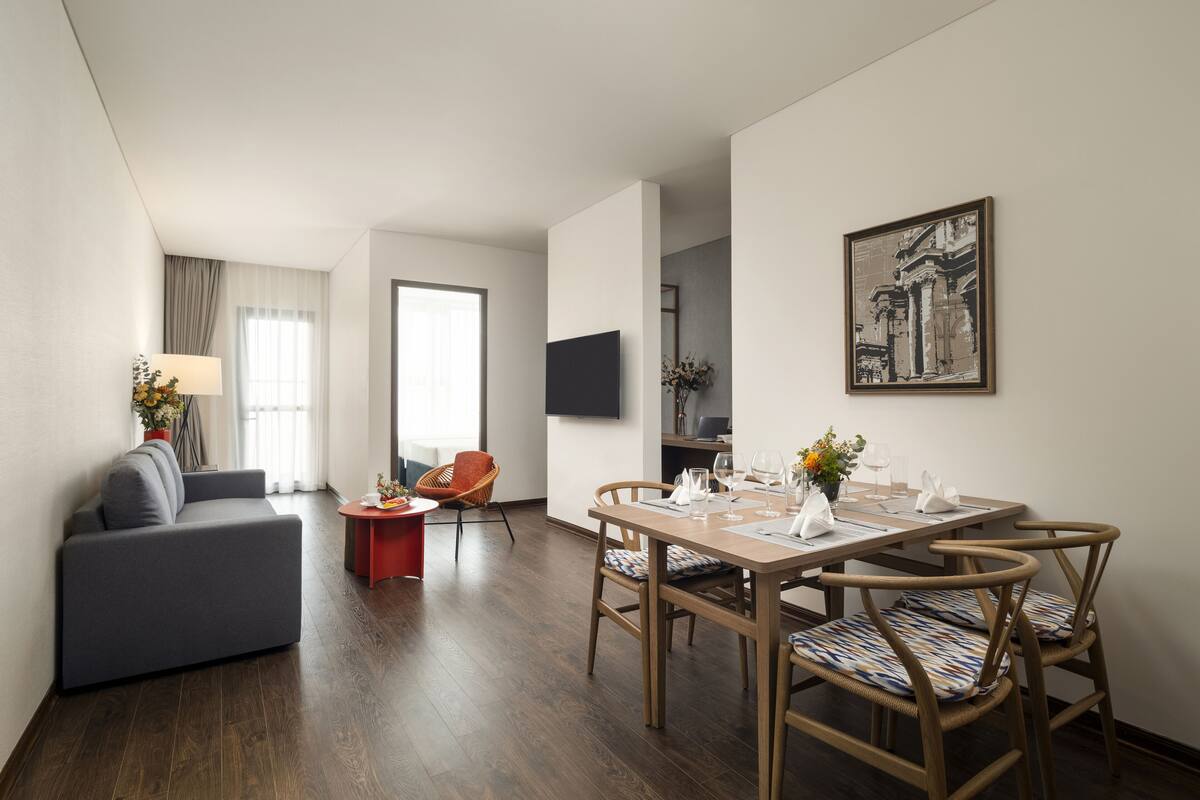 Una sala de estar moderna con un sofá, una mesa de comedor, sillas y un televisor.