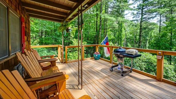 A wooden deck with outdoor seating, a flag, and a grill cart.