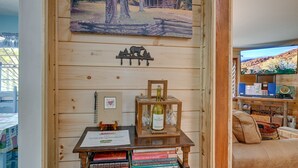 A wooden interior with a table displaying books, a wine bottle, and a bear decoration.