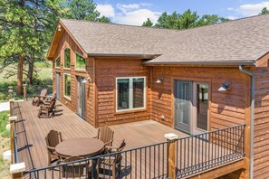 Een houten chalet met terras, grote ramen en een eethoek.