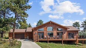 Ein zweistöckiges Holzhaus mit überdachter Terrasse und Garage.