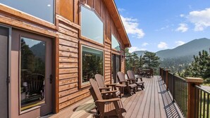 Eine Holzblockhütte mit einer Terrasse, großen Fenstern und Bergblick.