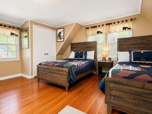A bedroom with two wooden beds, a window with curtains, a door, and a painting on the wall. - Country Bear Inn - Game Room, Pool Table, Barbecue (Big Bear City)